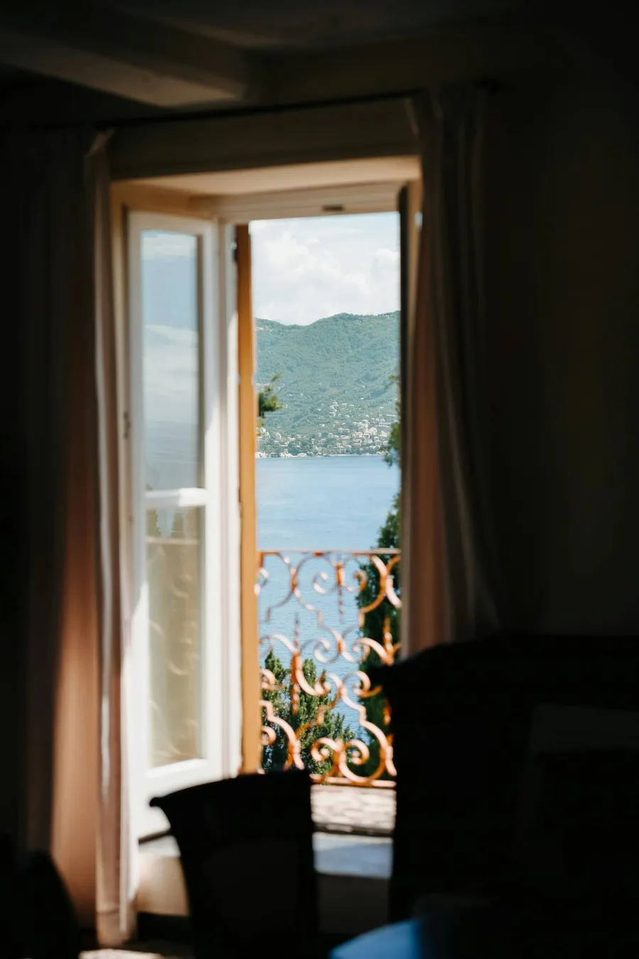 An open window looking out over a lake and green hills